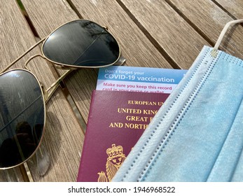 London, UK - 03.31.2021: Covid 19 Vaccine Passport Concept  For Restrictions On Travel With Sunglasses, UK Passport And Covid Mask And Vaccine ID Card 