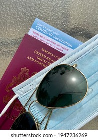 London, UK - 03.31.2021: Covid 19 Vaccine Passport Concept  For Restrictions On Travel With Sunglasses, UK Passport And Covid Mask And Vaccine ID Card 