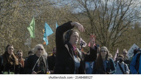 London, UK - 04 09 2022: A female climate protester conductor leading a group of percussionists beating on drums, for an Extinction Rebellion climate protest.