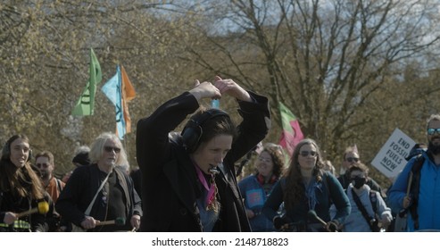 London, UK - 04 09 2022: A female climate protester conductor leading a group of percussionists beating on drums, for an Extinction Rebellion climate protest.