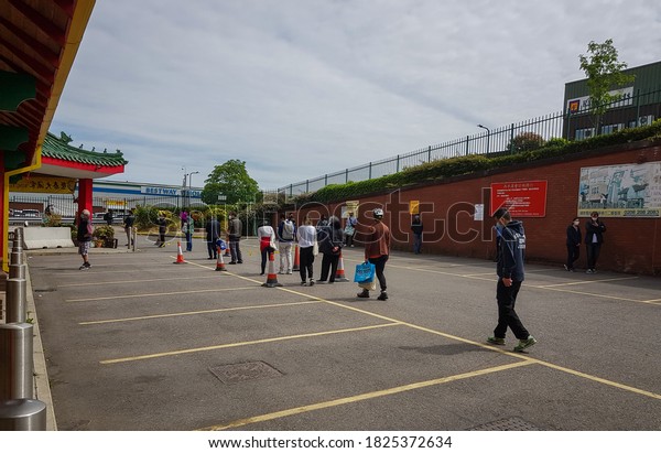 London. UK- 05.17.2020: a long\
queue of people in the car park of Wing Yip Chinese supermarket\
wearing face mask and social distancing waiting for their turn to\
shop.