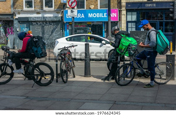 London. UK- 05.18.2021: young men\
working as self employed riders for online food ordering companies\
waiting for their next job notice to make home\
deliveries.