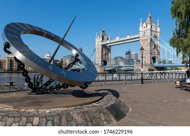 London. UK- 05.30.2020: The Timepiece Sundial Sculpture In St. Katherine Dock Marina With A View Of The Thames River And Tower Bridge In The Background On A Beautiful Sunny Blue Sky Spring Day.