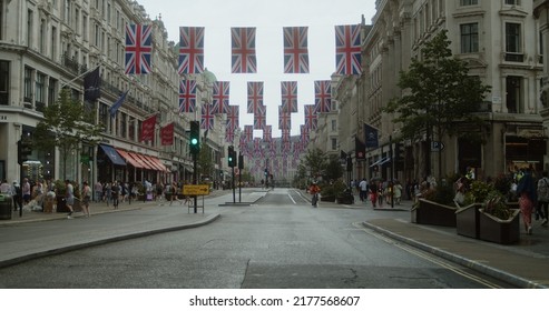 London, UK - 06 18 2022: An Empty Road With Union Jack Flags Hanging Overhead For The Queen Platinum Jubilee, Crowd Ready To March From Portland Place To Parliament Square, ‘We Demand Better March’.