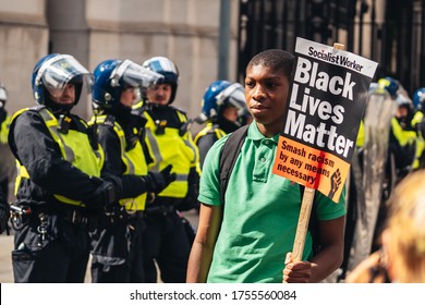 London / UK - 06/13/2020: Black Lives Matter Protest During Lockdown Coronavirus Pandemic. Young Man With BLM Banner Posing In Front Of Police Officers