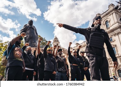 London / UK - 06/20/2020: Group of Black Lives Matters protesters in front of Sir Winston Churchill Monument statue recording video clip holding their fists in the air