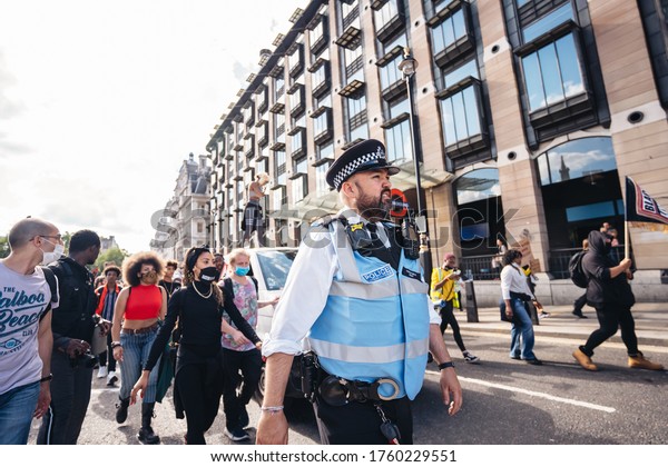 London / UK - 06/20/2020:\
Police officer in front of Huge crowd of Black Lives Matters\
protesters heading to Parliament Square, Westminster, chanting and\
holding banners