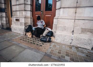 London / UK - 07/11/2020: Homeless Lady Sitting On The Pavement, Reading Book Wearing A Mask