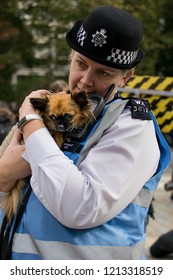 London, UK, 10/03/2018: A Female Metropolitan Police Officer Tenderly Holds A Tiny Dog In Her Arms.  