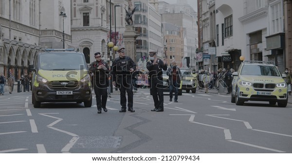 London, UK - 11 06 2021: City of London police\
officers walking on Strand street, ahead of a crowd of climate\
activists for COP26 ‘Global Day of Action for Climate Justice’\
march, during pandemic.