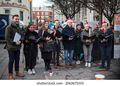 London, UK - 15 December 2020, Group Of Men And Women Wearing Santa Claus Hats Singing Christmas Carols At Covent Garden Raising Money To Support Animals In Shelters