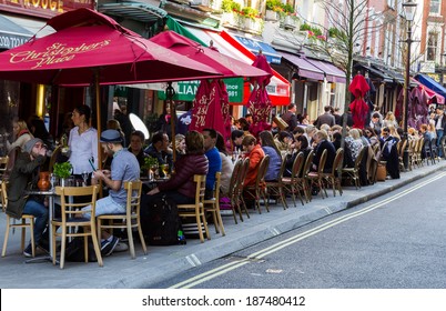 LONDON, UK - 15TH MARCH 2014: A Long Row Of Tables Outside Restaurants Near St Christophers Place With People Outside Drinking And Socializing