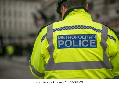 London, UK. 17th March 2018. EDITORIAL - Close Up View Of Police Sign On The Back Of A Metropolitan Police Officer's Yellow Reflective Jacket As He Goes About His Duties In Central London, UK.