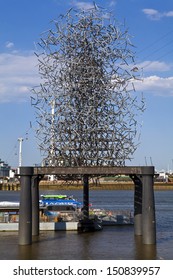 LONDON, UK - 1ST AUGUST 2013: Anthony Gormley's Quantum Cloud Sculpture On A Plinth On The River Thames In London.  The Emirates Air Line Cable Car Can Be Seen Behind It.