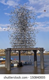 LONDON, UK - 1ST AUGUST 2013: Anthony Gormley's Quantum Cloud Sculpture On A Plinth On The River Thames In London.  The Emirates Air Line Cable Car Can Be Seen Behind It.