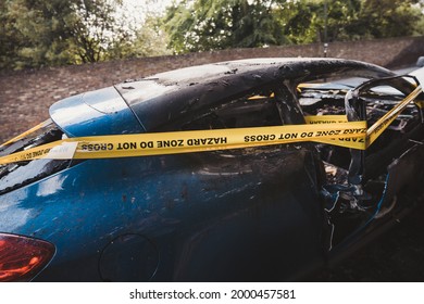 London | UK - 2021.06.12: An Abandoned, Stolen Burnt Out Blue Car Parked On The Sideway Parking Spot б Tied With Yellow Do Not Cross Stripe