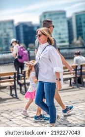 London, UK - 21 June, 2022: Young Woman Waking On The Thames River Walk At Summer Sunny Day.  Street Photography