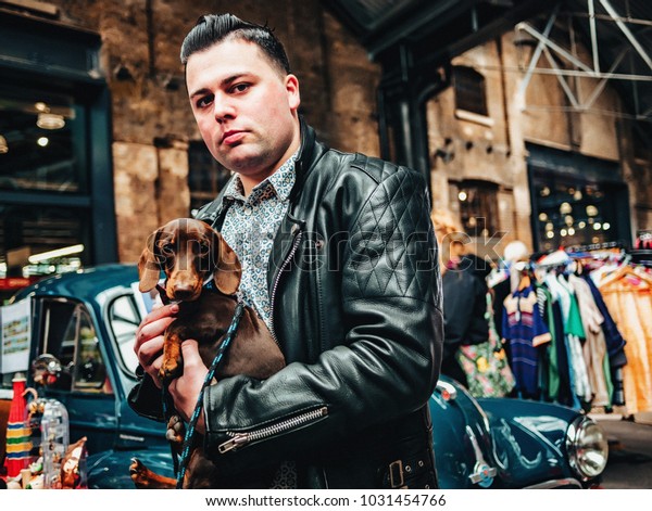 London / UK - 22.04.2017 : Stylish Guy With\
a Dog selling stuff on Classic Car Boot\
Sale