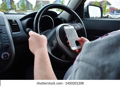 London, UK - 23 April 2019: A Woman Using A Phone Texting On Social Media While Driving A Car.