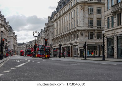 London, UK - 28 March 2020: Classic Red London Double Decker Buses Approaching Oxford Circus From Great Portland Street. Empty Streets. All Shops And Restaurants Closed Due To The Covid-19 Lockdown.