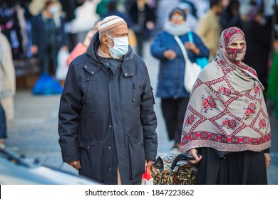 London, UK - 3 November, 2020 - An Asian Muslim Man And Woman Wearing A Mask And A Hijab As A Face Covering While Shopping At Walthamstow Market