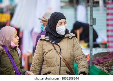 London, UK - 3 November, 2020 - An Asian Muslim woman wearing a face mask and a hijab while shopping at Walthamstow market