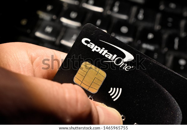 London,\
UK - 31 July 2019: A hand holding a capital one credit debit loan\
finance wireless contactless bank card and\
chip.