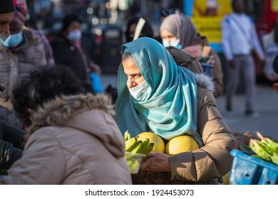 London, UK - 5 February, 2021 - A British Asian woman wearing a face mask while shopping at an outdoor produce stall on Wood Green high street