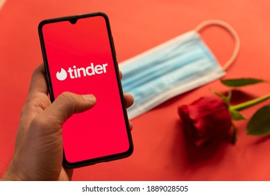 London, UK - 6 january 2021: tinder dating app logo on mobile phone with face mask and red rose. Concept of dating during covid19 pandemic