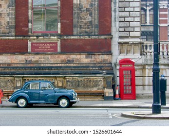 London / UK - April 05 2008: An Old Blue Car Is Parked In Front Of Victoria & Albert Museum And Next To Traditional English Red Phone Booth