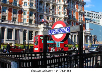 LONDON, UK - APRIL 10, 2019: London Underground Sign, Entrance To Knightsbridge Station, Red Double Decker Bus In Motion, Busy Street