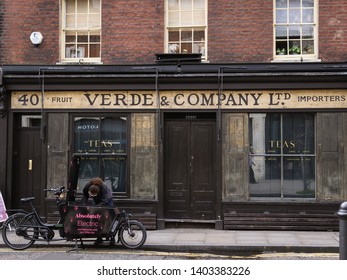 London, UK - April 12 19 : An electric rider is stopping to check for his bike in front of an old Verde & Company premise