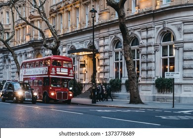 London, UK - April 13, 2019: Black Cab And An Afternoon Tea Bus Tour Inside Retro Red Double Decker Bus On A Street In London, UK, At Dusk. Double Decker Bus Is An Iconic Symbol Of The City.