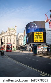 London, UK - April 2020: Piccadilly Circus During Coronavirus Lockdown. Stay Home Sign. NHS Support. Iconic London Landmark With Famous Billboard And Traditional London Bus.