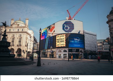 London, UK - April 2020: Piccadilly Circus during coronavirus lockdown. Stay home sign. NHS support. Iconic London landmark with famous billboard and traditional London bus.