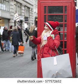 LONDON, UK - APRIL 22, 2016: Blonde In Red Coat Makes Selfie Near Red London Phone Booth.