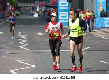 London, UK - April 23, 2017: London Marathon, Disabled Athlete Running Distance With Guide Runners In Canary Wharf