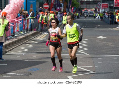 London, UK - April 23, 2017: London Marathon, Disabled Athlete Running Distance With Guide Runners In Canary Wharf