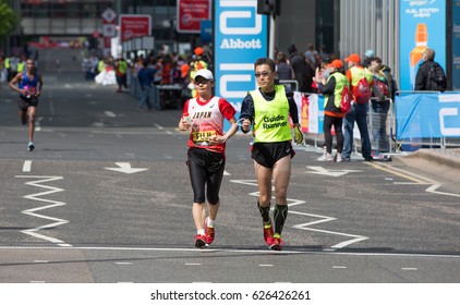 London, UK - April 23, 2017: London Marathon, Disabled Athlete Running Distance With Guide Runners In Canary Wharf