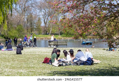 London, UK - April 24, 2021: Group Of People Enjoying A Sunny Day In A Park In The South Of London. Young People In A Picnic, Bikes And A Beautiful Lake In The Background.