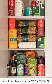 London, UK: April 8, 2022: Cupboard shelves full of food provision, such as pasta, rice, porridge, canned tuna, beans and more. Panic buying to survive pandemic or food crisis