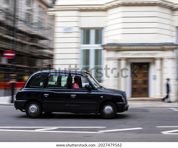 London, UK - August 12th 2021: A panning shot of a\
London Taxi, also known as a black cab, driving through central\
London, UK. 