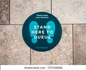 London UK, August 16th 2020: "Stand here to queue" floor sticker sign in shopping mall. Stratford Westfield, East London. Social distancing measures during Covid-19, Coronavirus pandemic. 