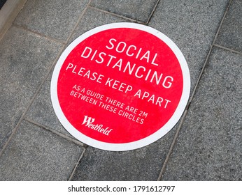 London UK, August 1st, 2020: A red circular pavement floor sticker sign. For social distancing, please keep apart. Westfield shopping centre, Stratford, East London. Covid-19 and coronavirus. 