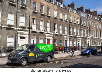 London, UK - August  2019: Zipcar Van For Car Sharing Parked In A Local Street With Luxury Property Tenement Houses In Georgian British Style In Central London.