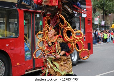 London, UK - August 27, 2018: Woman In Carnival Costume Chasing A Bus,  Notting Hill Carnival