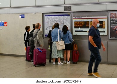 London, UK - August 27th 2021: Passengers with roller luggage at Kings Cross St Pancras check the route they should take using a map of the London Underground