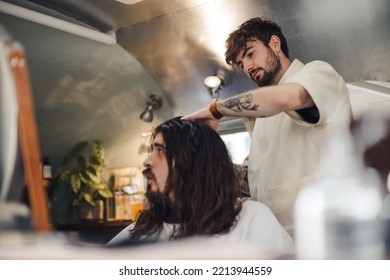 London UK - August 7, 2021:  Hairstylist Doing Haircut In Mobile Hair Salon At Classic Car Boot Sale, A Retro Culture Festival.