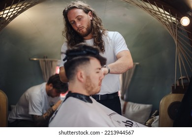 London UK - August 7, 2021:  Hairstylist Doing Haircut In Mobile Hair Salon At Classic Car Boot Sale, A Retro Culture Festival.