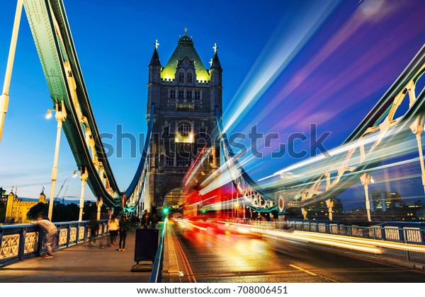 London, UK. Car traffic at Tower bridge at night in\
London, UK. Car light trails, motion blurred red bus with clear\
blue sky